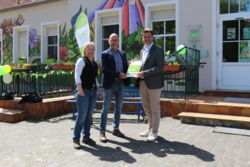 Drei Personen halten ein Stück Papier hoch.